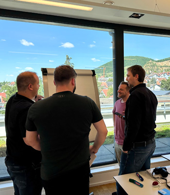 IT-Train-the-Trainer-Seminar mit Gruppenarbeit am Flipchart in hellem Seminarraum mit Praxisdiskussion